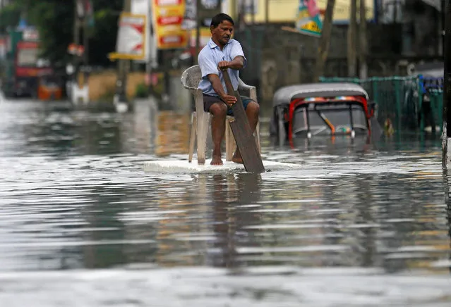 A man sits on a chair as he uses a piece of styrofoam to move through a flooded road in Wellampitiya, Sri Lanka May 21, 2016. (Photo by Dinuka Liyanawatte/Reuters)