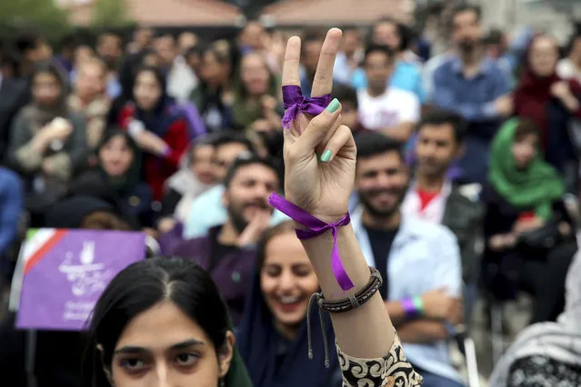 A supporter of Iran's President Hassan Rouhani, who is running for a second term in office, makes V sign as she watches a live televised debate outside a Rouhani campaign headquarters in Tehran, Iran, Friday, May 12, 2017. Rivals of President Hassan Rouhani in the May 19 poll have renewed accusations of corruption and mismanagement against him during the last of three televised debates. (Photo by Ebrahim Noroozi/AP Photo)