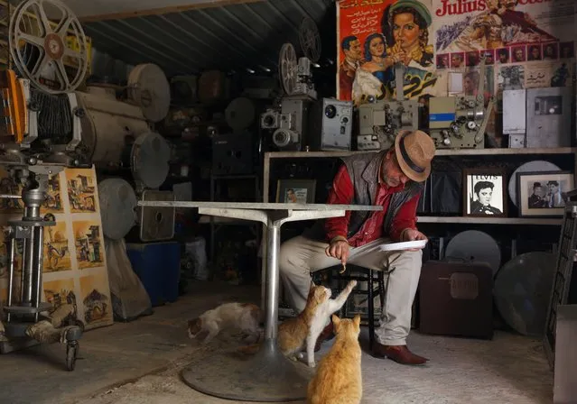Mohammed Dakhil Chyad, 55, an Iraqi cinephile who offers free screenings in his home cinema and at a cultural center, feeds his cats in Baghdad, Iraq, March 29, 2022. (Photo by Tiba Sadeq/Reuters)