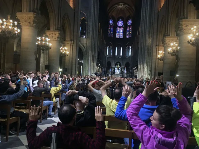 In this image provided by Nancy Soderberg, people inside Notre Dame cathedral sit with their hands in the air, after an attack on police in Paris, Tuesday, June 6, 2017. Paris prosecutors have opened a counterterrorism investigation after an unidentified assailant attacked police with a hammer outside Notre Dame Cathedral. French Interior Minister Gerard Collomb says the attacker cried “it's for Syria” as he went after officers patrolling an esplanade in front of the famous landmark. (Photo by Nancy Soderberg via AP Photo)