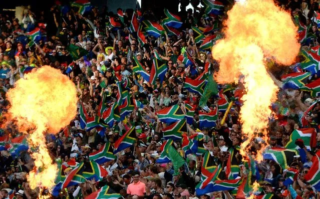 South Africa's supporters wave the national flag as they cheer for their team while fire flames raise from the pitch during the HSBC World Rugby Sevens Series men's final rugby match between New Zealand and South Africa at the Cape Town Stadium in Cape Town, on December 15, 2019. (Photo by Rodger Bosch/AFP Photo)