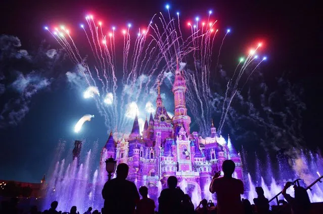 This photo taken on June 16, 2017 shows visitors watching fireworks exploding over the castle at an event to mark the first anniversary of the opening of Shanghai Disneyland, in Shanghai. (Photo by AFP Photo/Stringer)