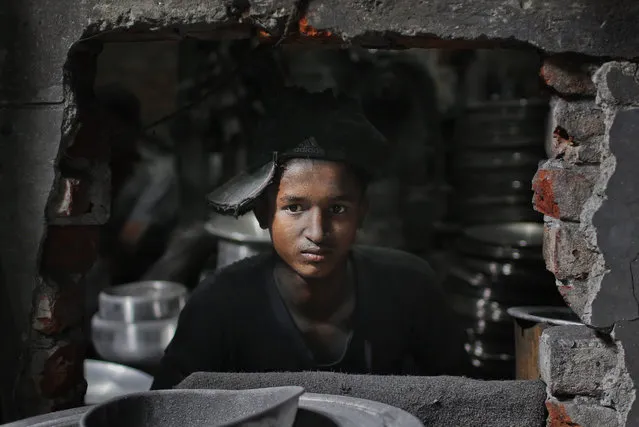 Bangladeshi boy Rubel, 12, looks towards camera as he works at a factory that makes metal utensils in Dhaka, Bangladesh, Sunday, June 12, 2016. He earns less than $5 per day. The World Day Against Child Labor, which was initiated in 2002 by the International Labor Organization to highlight the plight of child laborers, is observed across the world on June 12. (Photo by A.M. Ahad/AP Photo)