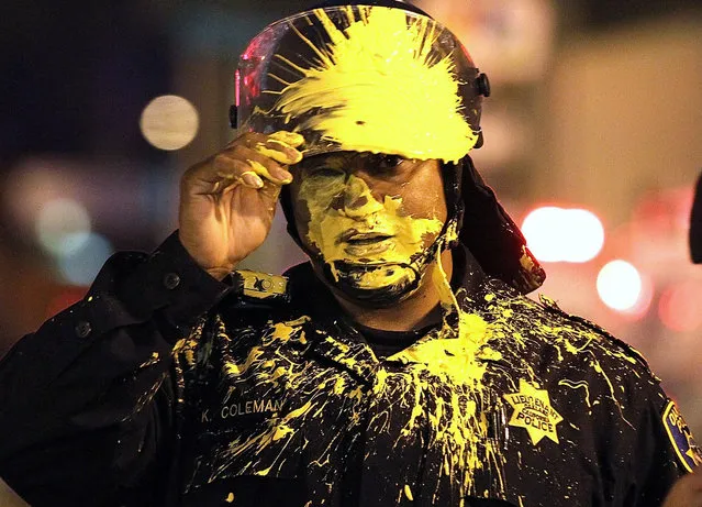 An Oakland police officer pauses after being hit in the face with paint as officers advanced on Occupy protesters blocking an intersection during a May Day demonstration  in Oakland, California on May 2, 2012