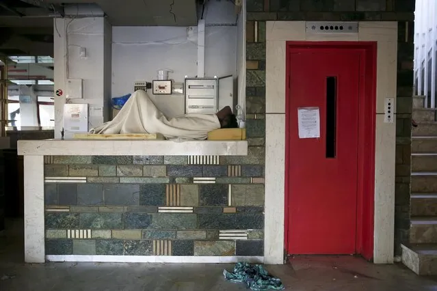 A migrant from Pakistan sleeps at the reception desk of a deserted hotel on the Greek island of Kos, August 13, 2015. (Photo by Alkis Konstantinidis/Reuters)