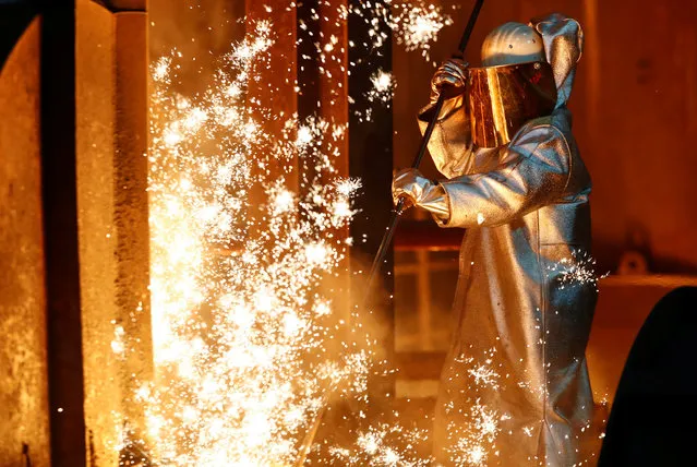 A steel worker of ThyssenKrupp stands amid sparks of raw iron coming from a blast furnace at a ThyssenKrupp steel factory in Duisburg, western Germany, January 30, 2020. (Photo by Wolfgang Rattay/Reuters)