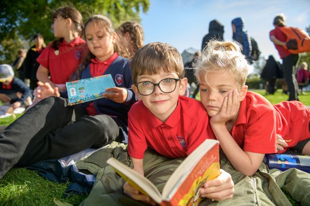 Year 4 pupils Billy, centre, and Eddie, right, from Christ Church CoE Primary School, relax with a book at Montpellier Gardens during a visit to The Times and Sunday Times Cheltenham Literature Festival in UK early October 2024. (Photo by Adrian Sherratt for the Times)