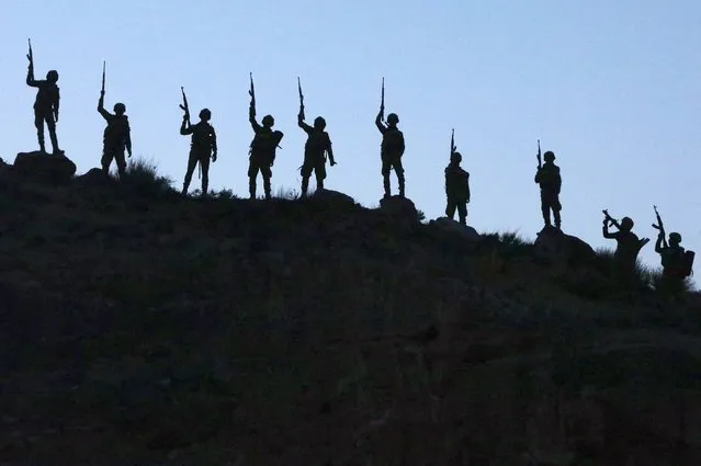 Turkey-backed Syrian fighters raise their weapons as they take part in a military excercise in the countryside of the northern city of Manbij, on June 2, 2022. Turkey's President Recep Tayyip Erdogan on June 1 renewed threats of a military offensive in northern Syria, which he said would target Kurdish “terrorists”. (Photo by Bakr Alkasem/AFP Photo)