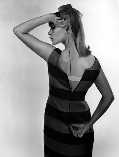 A model demonstrating how to zip up the back of a dress when there's no one around to give a hand - using a piece of string looped through the hole in the top of the zip tag; 1964