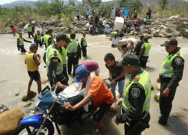 Colombian police stand by as some of their countrymen move their belongings across the Tachira River into Colombia's community of La Parada, across the border with San Antonio del Tachira, Venezuela, Tuesday, August 25, 2015. (Photo by Efrain Patino/AP Photo)