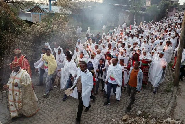 Ethiopian Orthodox faithful hold candles as they receive a blessing from a priest with an incense smoke which according to their belief will keep the coronavirus disease (COVID-19) away, in Addis Ababa, Ethiopia on March 26, 2020. (Photo by Tiksa Negeri/Reuters)