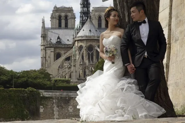 A Chinese couple poses during a pre-wedding photoshoot in front of the Notre-Dame Cathedral in Paris, France, August 28, 2015. (Photo by Philippe Wojazer/Reuters)