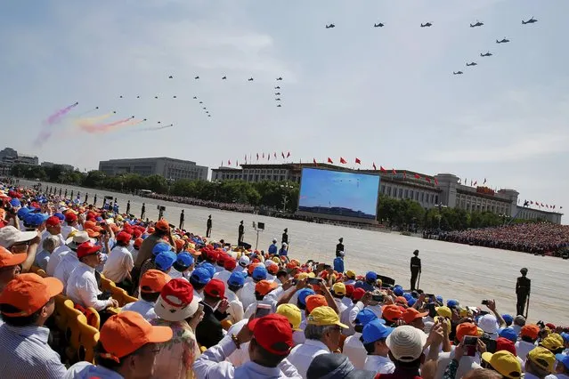 People watch while paramilitary policemen stand guard as military helicopters perform during the military parade marking the 70th anniversary of the end of World War Two, in Beijing, China, September 3, 2015. (Photo by Damir Sagolj/Reuters)