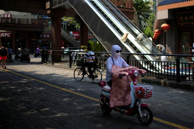 A woman, wearing a hood, mask and sunglasses to block the sun's rays, rides an electric bicycle in Hangzhou, Zhejiang province, China, July 29, 2016. (Photo by Aly Song/Reuters)