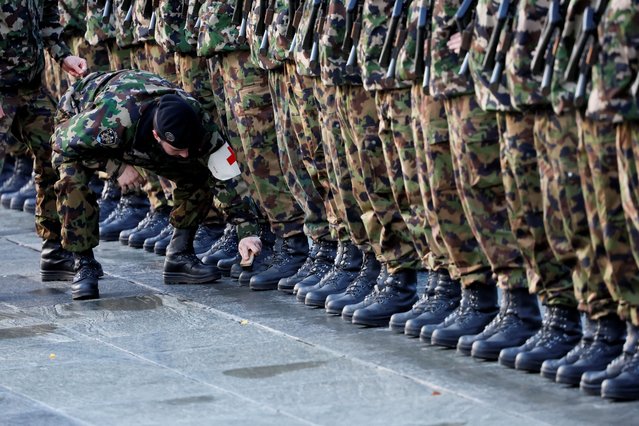 A soldier cleans the boots of his comrades, before Swiss President Alain Berset and French President Emmanuel Macron review the troops during a state visit at the Federal Square in Bern, Switzerland on November 15, 2023. (Photo by Denis Balibouse/Reuters)