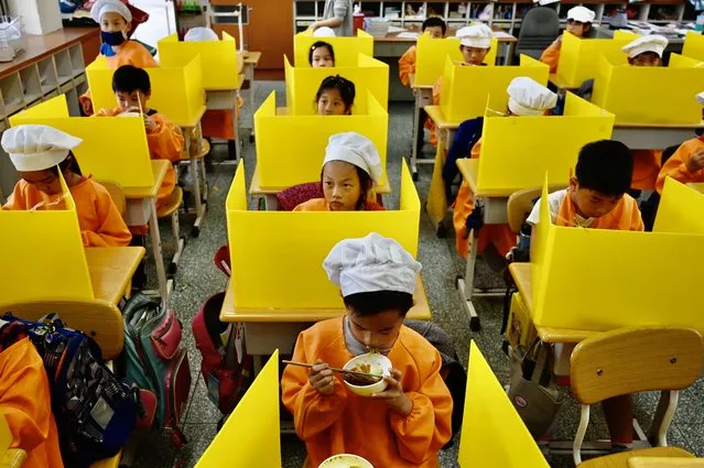 Students eat their lunch on desks with plastic partitions as a preventive measure to curb the spread of the COVID-19 coronavirus at Dajia Elementary School in Taipei on April 29, 2020. (Photo by Sam Yeh/AFP Photo)