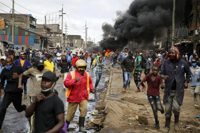 Residents and protesters flee during clashes with police next to burning tyre barricades in the Kariobangi slum of Nairobi, Kenya Friday, May 8, 2020. (Photo by Brian Inganga/AP Photo)