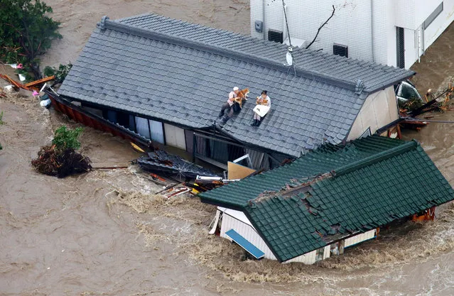Residents holding dogs wait for help, sitting on the roof of their house in the flooded city of  Joso, Ibaraki prefecture, northeast of Tokyo Thursday, September 10, 2015. (Photo by Kyodo News via AP Photo)
