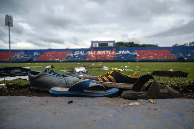 Discarded shoes sit by the pitch at Kanjuruhan stadium days after a deadly stampede following a football match in Malang, East Java on October 3, 2022. Anger against police mounted in Indonesia on October 3 after at least 125 people were killed in one of the deadliest disasters in the history of football, when officers fired tear gas in a packed stadium, triggering a stampede. (Photo by Juni Kriswanto/AFP Photo)