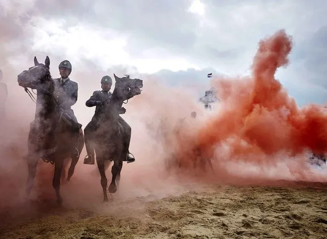 Smoke from grenades shrouds horses and riders during a practice session for members of the Dutch cavalry in Scheveningen, Netherlands, Monday, September 14, 2015. About 80 horses and riders were rehearsing on a beach in the coastal resort of Scheveningen, outside The Hague, for ceremonies which will be held Tuesday to mark the opening of parliament. (Photo by Phil Nijhuis/AP Photo)