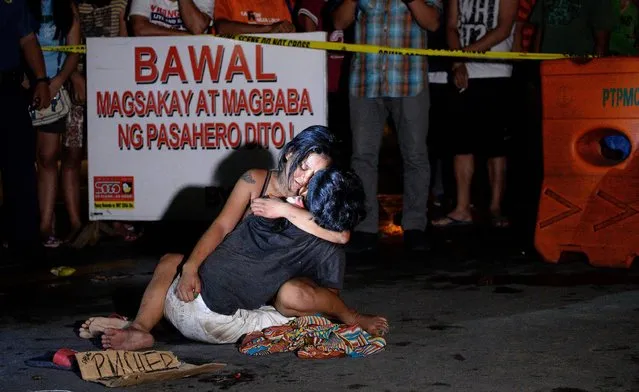 This file photo taken on July 23, 2016 shows Jennilyn Olayres hugging the dead body of her partner Michael Siaron who was shot by unidentified gunman and left with a cardboard sign with a message “I'm a pusher” along a street in Manila. Hundreds of people have died since President Rodrigo Duterte won a landslide election in May, promising to rid society of drugs and crime in six months by killing tens of thousands of criminals. Police figures showed this week that 402 drug suspects had been killed a month into Duterte's presidency. This figure does not include those slain by suspected vigilantes. (Photo by Noel Celis/AFP Photo)