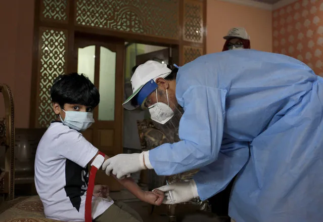 A health worker takes blood sample of a boy during door-to-door testing and screening facility for the coronavirus, Wednesday, June 10, 2020. Pakistan's coronavirus infections soared as the World Health Organization urged the government to impose a two-week lockdown to stem the relentless spike in new cases. (Photo by Anjum Naveed/AP Photo)