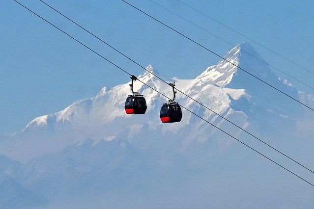 In this photograph taken on February 3, 2025, people ride on cable cars at Chandragiri hilltop on the outskirts of Kathmandu. (Photo by Prakash Mathema/AFP Photo)