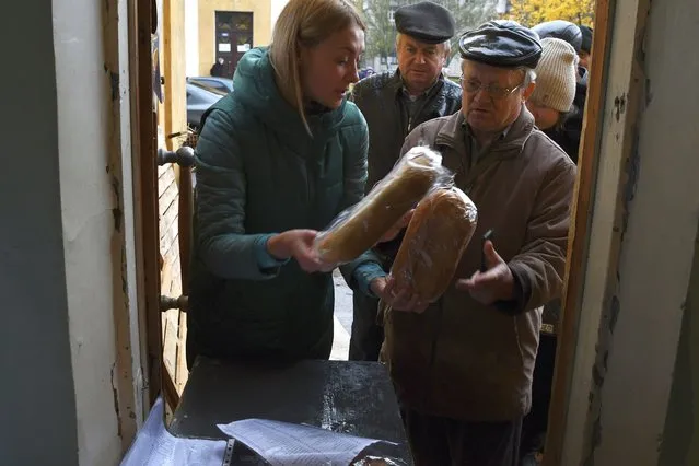 People receive bread at humanitarian aid center in Kramatorsk, Ukraine, Wednesday, October 26, 2022. (Photo by Andriy Andriyenko/AP Photo)