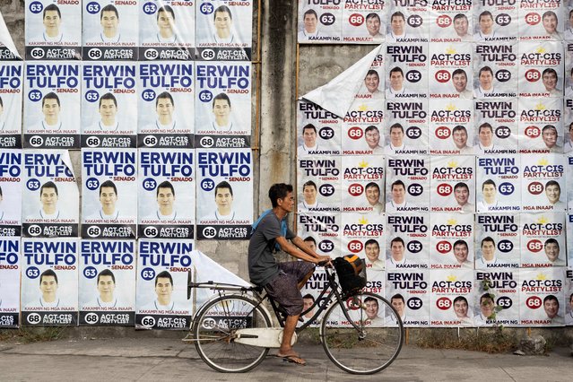 A man bikes past a wall of campaign posters for senatorial candidate Erwin Tulfo on the first day of the campaign period for the May 12 midterm elections, in Manila, Philippines, on February 11, 2025. (Photo by Eloisa Lopez/Reuters)