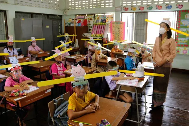 A teacher and students wearing hats designed for space keeper, practice social distancing to help curb the spread of the coronavirus at Ban Pa Muad School in Chiang Mai, north of Thailand on Friday, July 3, 2020. (Photo by Wichai Taprieu/AP Photo)