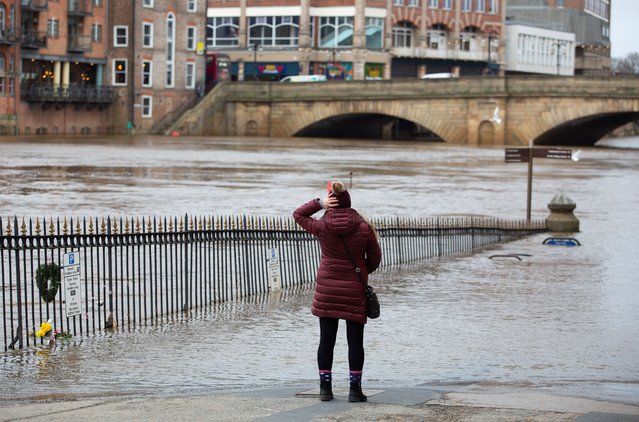 A woman stands beside the flooded banks of the River Ouse in York, England on January 24, 2024 as Storm Jocelyn brings strong winds and rain, prompting further weather warnings across the UK. (Photo by Richard Saker/The Guardian)