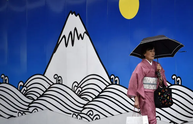 A woman clad in a kimono walks in front of a decorated construction site wall at Ginza shopping district in Tokyo, Japan, 27 June 2016. Tokyo stocks rebounded after dropping sharply on 24 June following the Brexit vote. The Nikkei Stock Average gained 357.19 points, or 2.39 percent, to close at 15,309.21. (Photo by Franck Robichon/EPA)