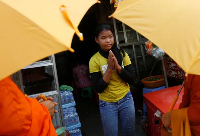 A girl prays as she offers some food to Buddhist monks along a street in Phnom Penh, Cambodia, September 6, 2016. (Photo by Samrang Pring/Reuters)