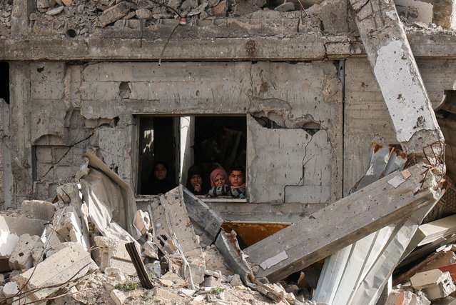 Palestinians look on as a crowd (not pictured) inspects the site of an Israeli strike on a house, in Khan Younis in the southern Gaza Strip on April 6, 2025. (Photo by Hatem Khaled/Reuters)