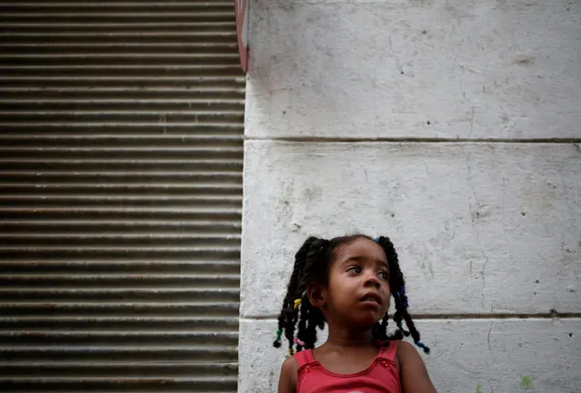 A girl watches the annual procession of Our Lady of Charity, the patron saint of Cuba, on the streets of downtown Havana, Cuba, September 8, 2016. (Photo by Enrique De La Osa/Reuters)