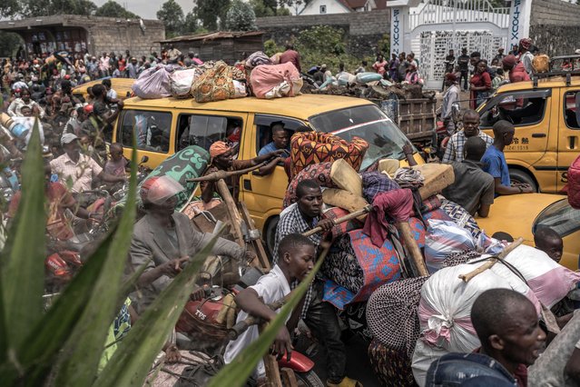 People gather at a busy road while carrying some of their belongings as they flee the Masisi territory following clashes between M23 rebels and government forces, at a road near Sake on February 7, 2024. Conflict between M23 rebels and government forces is intensifying in eastern DR Congo's Masisi territory, residents said on February 7, 2024 after days of unrest that have left dozens injured. Tensions in Masisi have displaced residents of many villages and overwhelmed health centres, according to humanitarian sources. (Photo by Aubin Mukoni/AFP Photo)