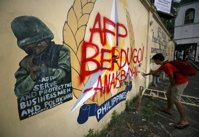 A youth activist vandalises the seal of the Armed Forces of the Philippines (AFP) outside their headquarters in Camp Aguinaldo, Quezon City, metro Manila September 4, 2015. A group of activists threw paint bombs and vandalised the gates of the AFP's headquarters to protest against the supposed killing of indigenous people in Mindanao, southern Philippines, by members of the military, according to a press statement from the activists. (Photo by Al Falcon/Reuters)