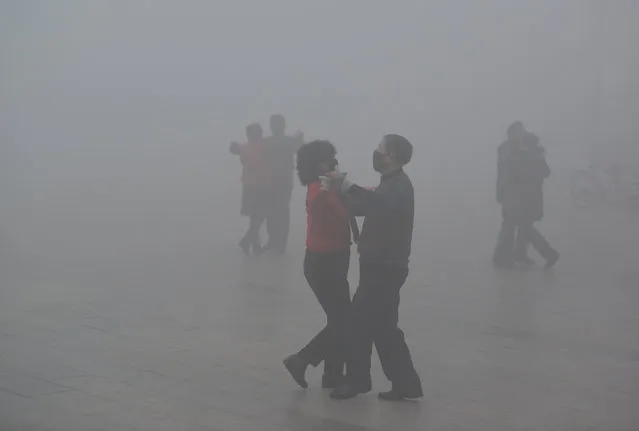People wearing masks dance at a square among heavy smog during a polluted day in Fuyang, Anhui province, China, January 3, 2017. (Photo by Reuters/China Daily)