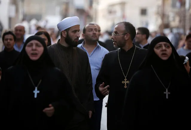 A Muslim Sheikh (C-L) chats with a Christian priest while marching with nuns and faithful along a street during Saidnaya Festival, near Damascus, Syria September 7, 2016. (Photo by Omar Sanadiki/Reuters)