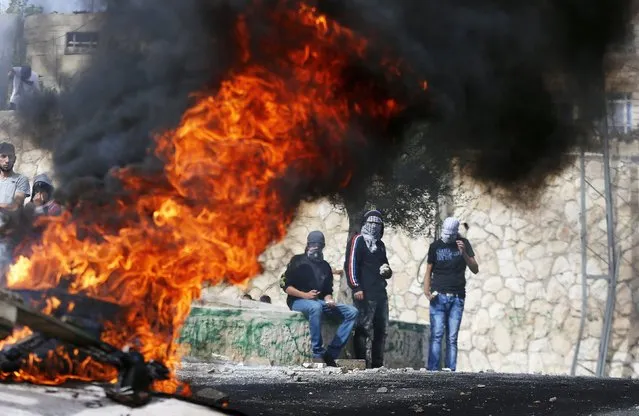 Stone-throwing Palestinian youths stand next to a fire during clashes with Israeli police in Sur Baher, a village in the suburbs of Arab east Jerusalem October 7, 2015. (Photo by Ammar Awad/Reuters)