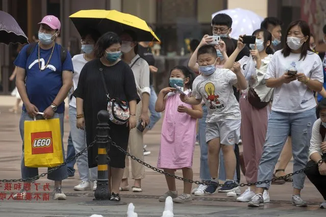 Residents wearing mask to protect from the coronavirus react as they watch a water fountain at a retail street in Beijing, China on Saturday, August 29, 2020. About one-third of students returned to school in the Chinese capital on Saturday in a staggered start to the new school year because of the coronavirus. (Photo by Ng Han Guan/AP Photo)