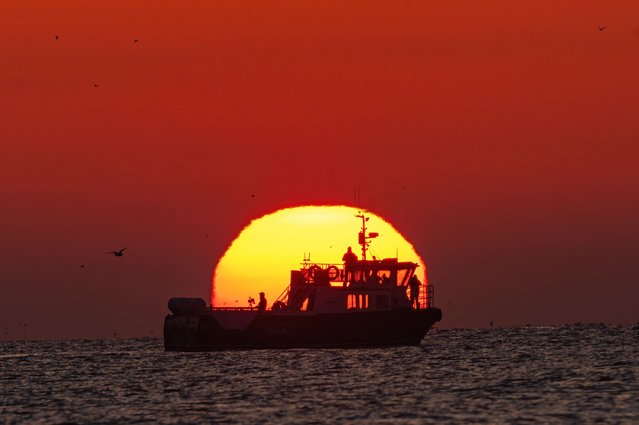The sun rises behind a boat with a camera crew at broad sands beach in East Lothian, Scotland on April 10, 2025. (Photo by Euan Cherry)