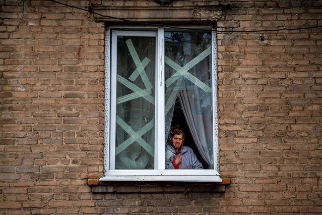 A local resident stands behind the broken window of her home in Chasiv Yar, eastern Ukraine, on January 5, 2023, amid the Russian invasion of Ukraine. (Photo by Dimitar Dilkoff/AFP Photo)