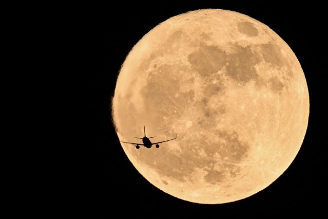 An aircraft passes in front of the full moon, known as the “Strawberry Moon” in Chongqing, southwest China on June 11, 2025. (Photo by Hector Retamal/AFP Photo)