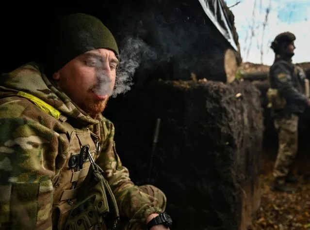 A serviceman smokes in a trench at his position on a front line in Zaporizhzhia region, Ukraine on November 3, 2022. (Photo by Reuters/Stringer)