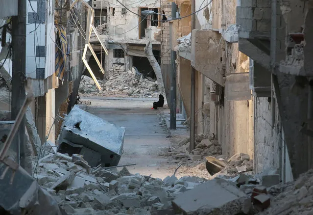 A woman sits amid damaged buildings in the rebel-held al-Myassar neighbourhood of Aleppo, Syria, September 27, 2016. (Photo by Abdalrhman Ismail/Reuters)