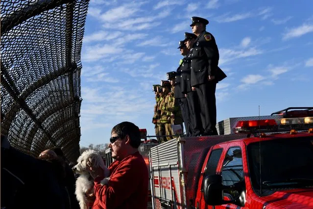 Roger Turek, holding his dog Jazzy, and members of the Rosedale Fire Department pay their respects from an overpass as the funeral procession for Detective Sean Suiter passes in Baltimore, USA on November 29, 2017. Suiter, an 18-year veteran, was killed Nov. 15 while conducting an investigation. (Photo by Katherine Frey/The Washington Post)