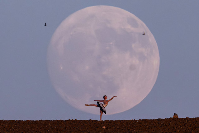 Ballerina Deniz Doga Usta performs as the Full Moon rises behind the mountains during evening time in capital city of Ankara, Turkiye on July 09, 2025. (Photo by Evrim Aydin/Anadolu via Getty Images)