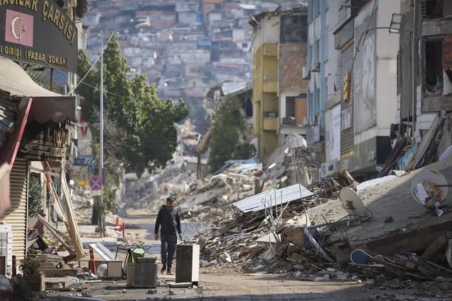 A man walks past destroyed buildings in Antakya, southeastern Turkey, Tuesday, February 21, 2023. The death toll in Turkey and Syria rose to eight in a new and powerful earthquake that struck two weeks after a devastating temblor killed nearly 45,000 people, authorities and media said Tuesday. (Photo by Unal Cam/AP Photo)