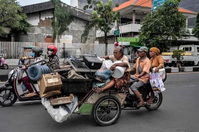 A family rides a becak (three-wheel vehicle) with used goods going for sale to a second-hand market in Surabaya on February 1, 2023. (Photo by Juni Kriswanto/AFP Photo)